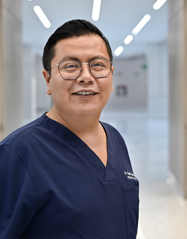 Es la foto de perfil de un cirujano plástico en Querétaro de Hospital Angeles Centro Sur. Usa un uniforme azul marino y lentes.