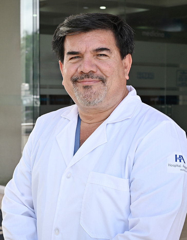 Es la foto de perfil de un pediatra y neonatólogo en Villahermosa de Hospital Angeles Villahermosa. Usa una bata blanca. Tiene el cabello negro y los brazos cruzados. Esta sonriendo.