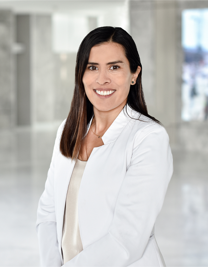 Es la foto de perfil de una reumatóloga en Querétaro de Hospital Angeles Centro Sur. Usa un saco blanco y una blusa beige. está sonriendo.