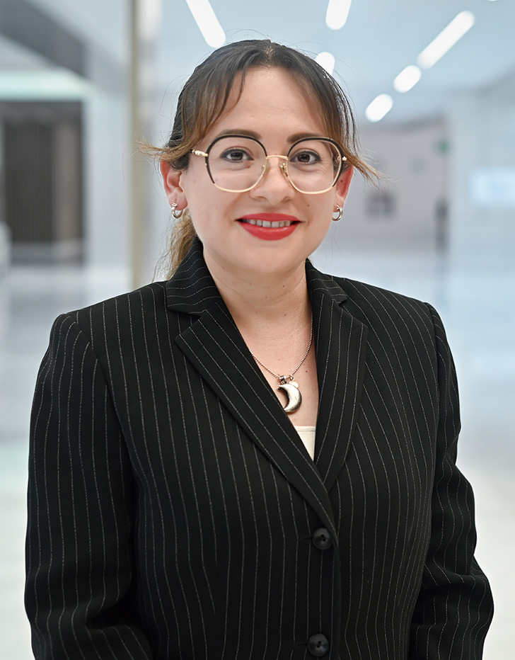 Es la foto de perfil de una oncóloga médica en Querétaro de Hospital Angeles Centro Sur. Usa un saco negro con franjas blancas delgadas y una blusa blanca.