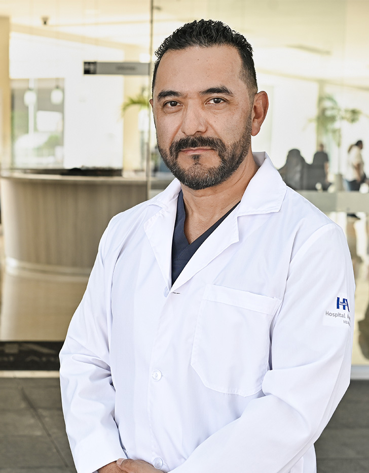 Es la foto de perfil de un otorrinolaringólogo en Ciudad de México de Hospital Angeles. El doctor tiene una bata blanca y una corbata azul marino con detalles en color blanco.