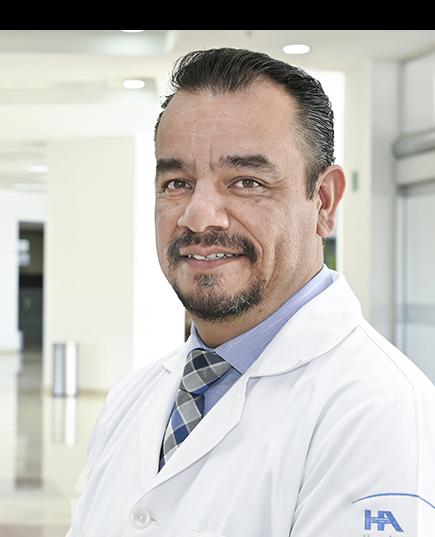 Es la foto de perfil de un cirujano general en Ciudad Juárez de Hospital Angeles Ciudad Juárez. El doctor viste una bata blanca y camisa azul cielo, tiene barba de candado.