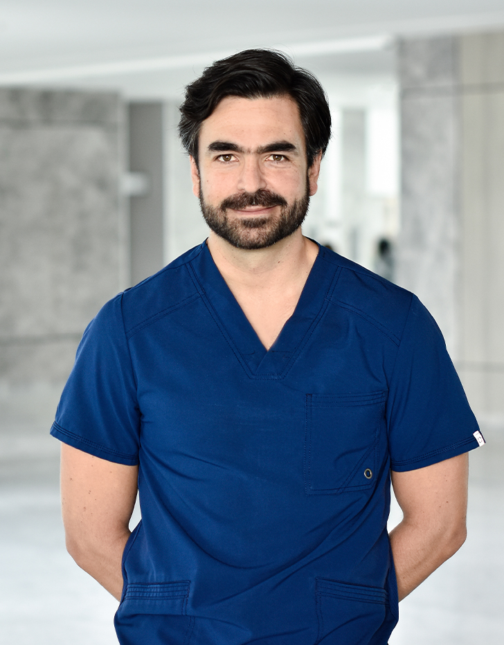 Es la foto de perfil de un ortopedista y traumatólogo en Querétaro de Hospital Angeles Centro Sur. Viste un uniforme azul, con cejas pobladas y barba oscura.