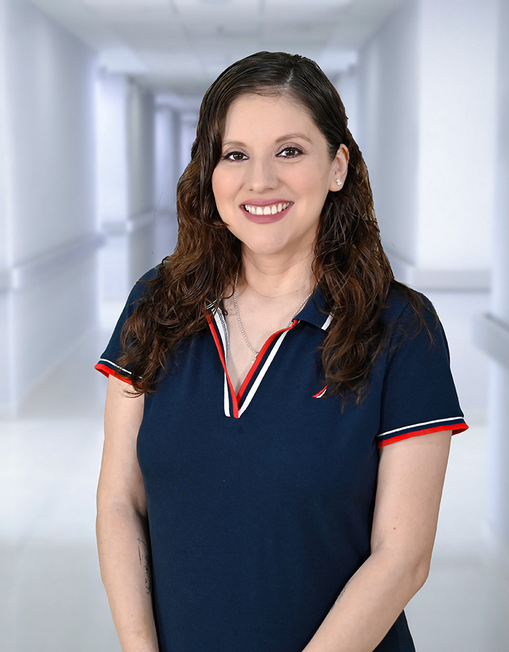Es la foto de perfil de una cardióloga en Ciudad Juárez de Hospital Angeles Ciudad Juárez. Viste una bata blanca con una blusa verde, es de tez blanca y tiene labial rojo.
