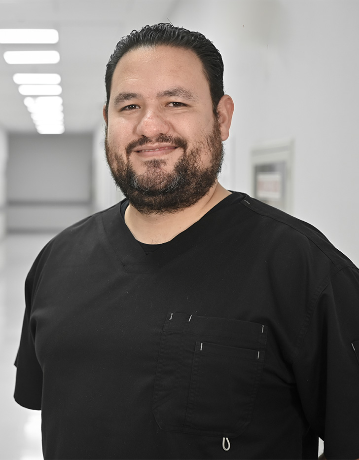 Es la foto de perfil de un internista especializado en gastroenterología y endoscopía en Ciudad de México de Hospital Angeles. El doctor tiene un uniforme negro, tiene barba y está sonriendo. 