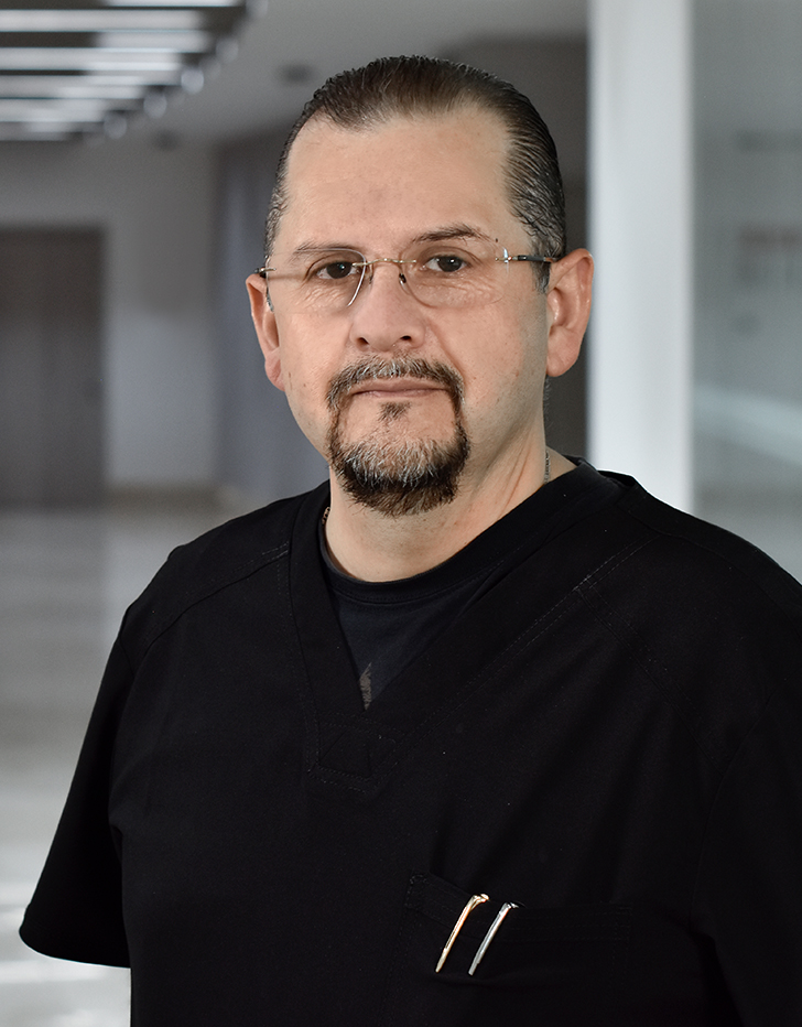 Es la foto de perfil de un anestesiólogo en Ciudad de México de Hospital Angeles. El doctor tiene lentes, barba de candado y viste un uniforme negro. 