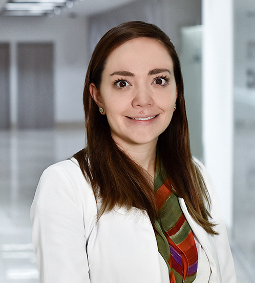 Es la foto de perfil de una internista en Huixquilucan de Hospital Angeles Lomas. Usa una bata blanca con una bufanda verde con vino, su cabello está por debajo de los hombros y está sonriendo.