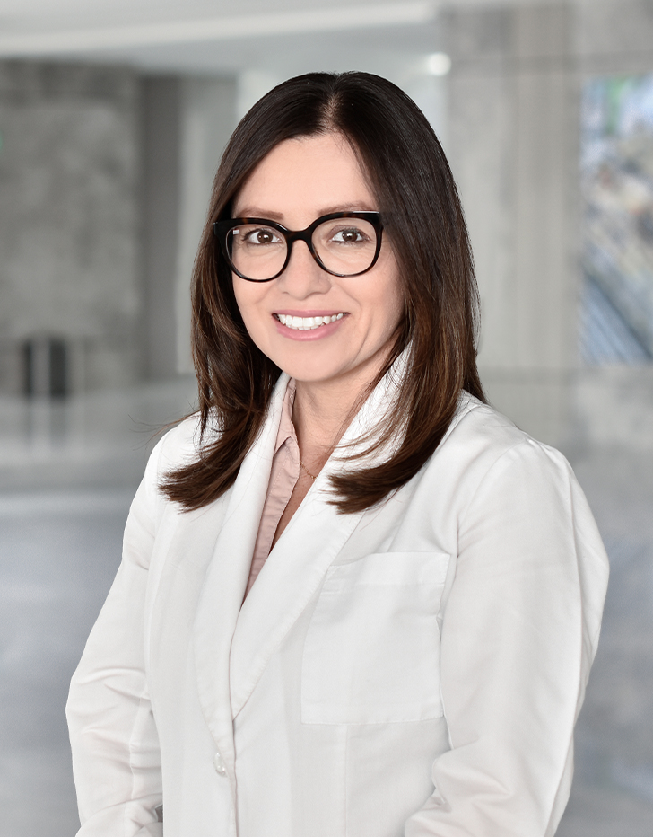 Es la foto de perfil de un otorrinolaringólogo en Querétaro de Hospital Angeles Centro Sur. Usa una bata blanca con una blusa rosa palo, tiene lentes con amrco negro semiredondos.