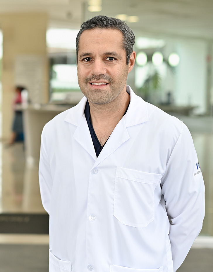 Es la foto de perfil de un ginecólogo y obstetra en Huixquilucan de Hospital Angeles Lomas. El doctor usa un uniforme negro con cuello V, es de cabello oscuro, tiene barba canosa y tez blanca.
