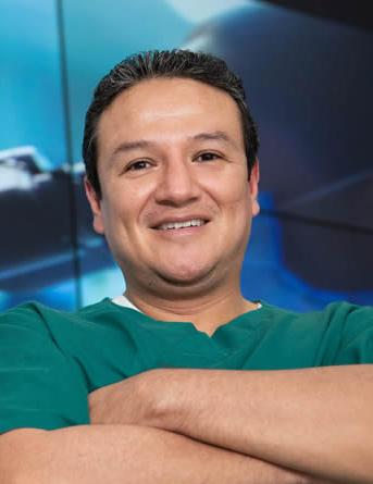 Es la foto de perfil de un cirujano oncológico en Ciudad de México de Hospital Angeles Clínica Londres. Utiliza un uniforme de color verde y está sonriendo.