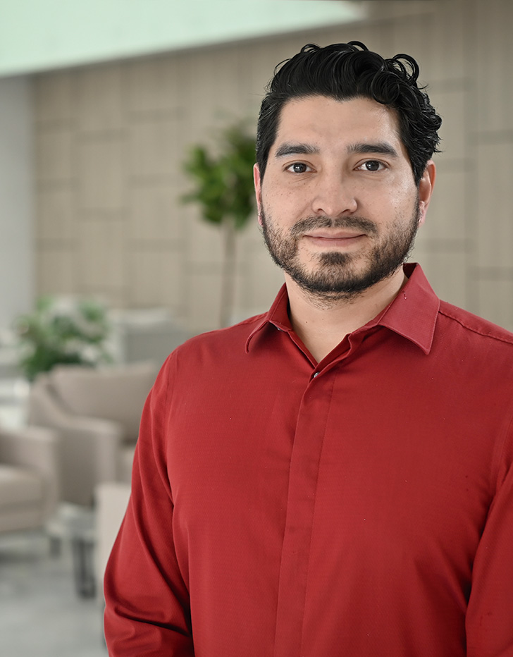 Es la foto de perfil de un cirujano oncológico en Querétaro de Hospital Angeles Centro Sur. Tiene una camisa roja barba y está sonriendo.