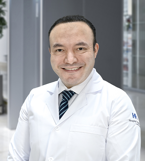 Es la foto de perfil de un ginecólogo en Huixquilucan de Hospital Angeles Lomas. Usa una bata blanca con camisa blanca y corbata azul. 