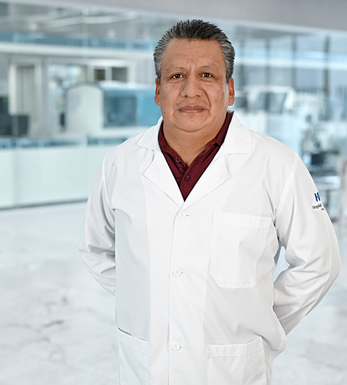 Es la foto de perfil de un cirujano neurológico especialista en terapia endovascular neurológica en Guadalajara de Hospital Angeles Del Carmen. Utiliza una bata blanca con una camisa rosa claro. 