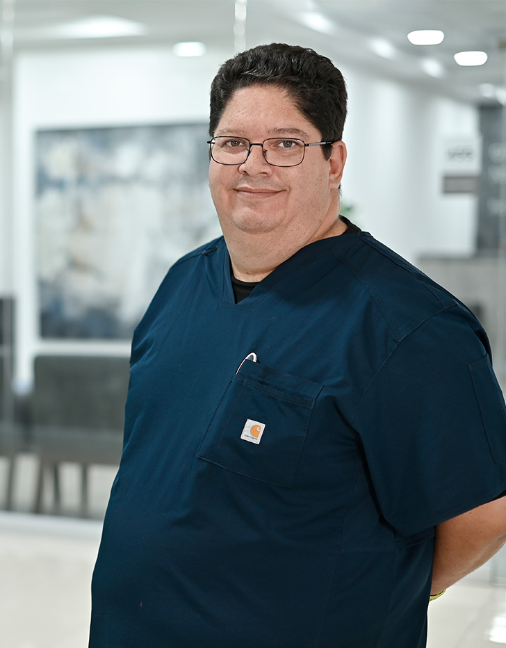 Es la foto de perfil de un urólogo en Ciudad de México de Hospital Angeles. Viste un uniforme negro, lentes y está sonriendo.