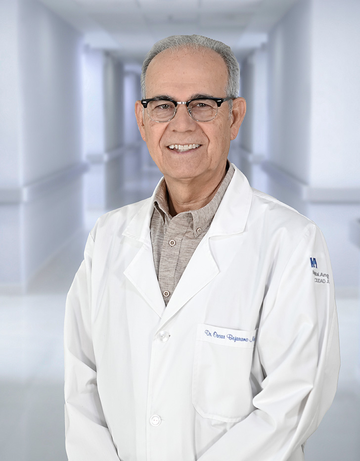 Es la foto de perfil de un ortopedista y traumatólogo en Ciudad Juárez de Hospital Angeles Ciudad Juárez. Utiliza una bata blanca con una camisa azul marino con detalles en blanco. Tiene lentes.