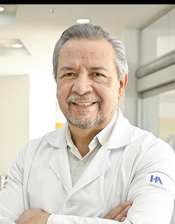 Es la foto de perfil de un internista en Ciudad Juárez de Hospital Angeles Ciudad Juárez. Utiliza una bata blanca, camisa beige y cabello canoso.