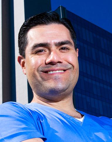 Es la foto de perfil de un ortopedista y traumatólogo en Ciudad de México de Hospital Angeles. Viste un uniforme azul claro, está sonriendo, tiene cejas pobladas y cabello oscuro.