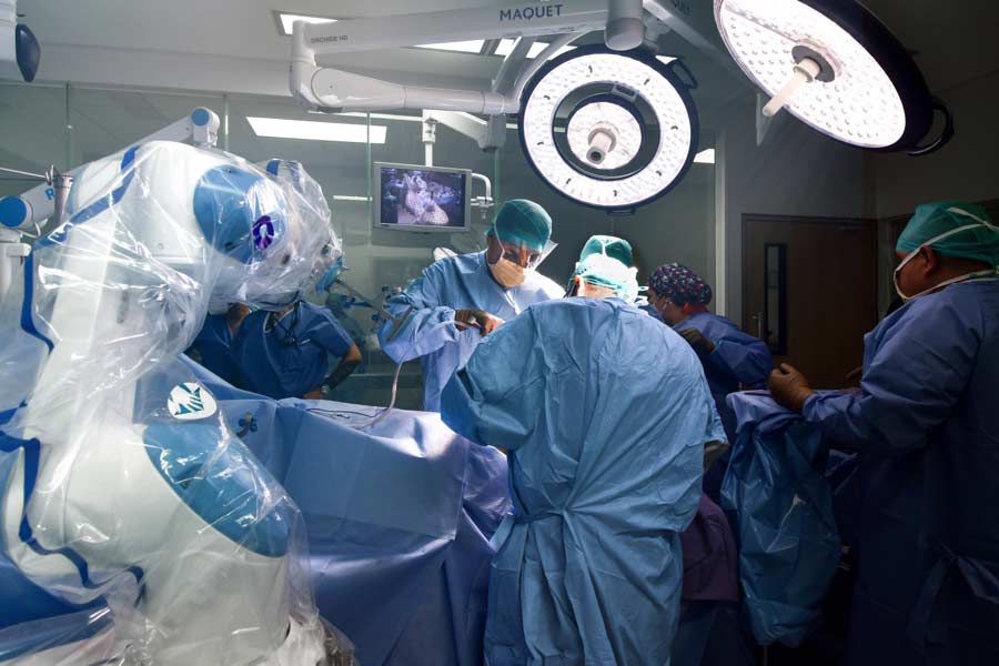 Seis médicos vestidos con pijamas azules, realizando un procedimiento quirúrgico